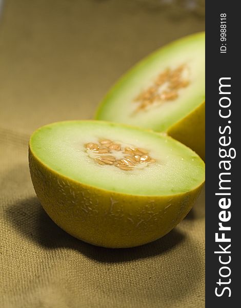 View of a sliced yellow melon in half on top of a fabric. View of a sliced yellow melon in half on top of a fabric.