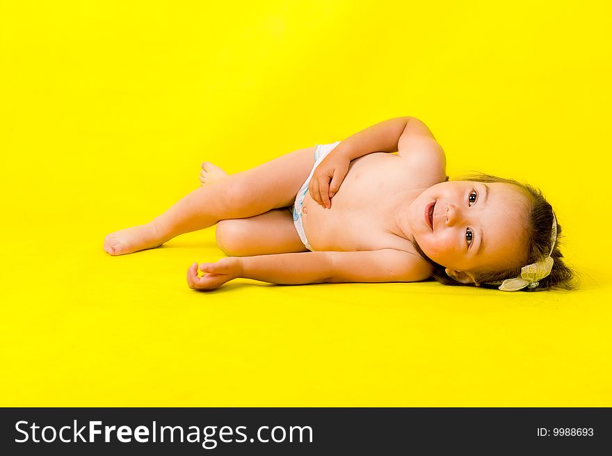 Cute little girl on the floor over yellow