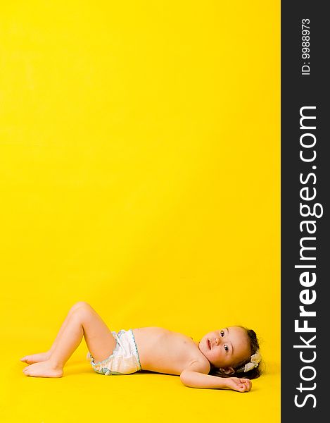 Cute little girl on the floor over yellow. Many lot of copyspace