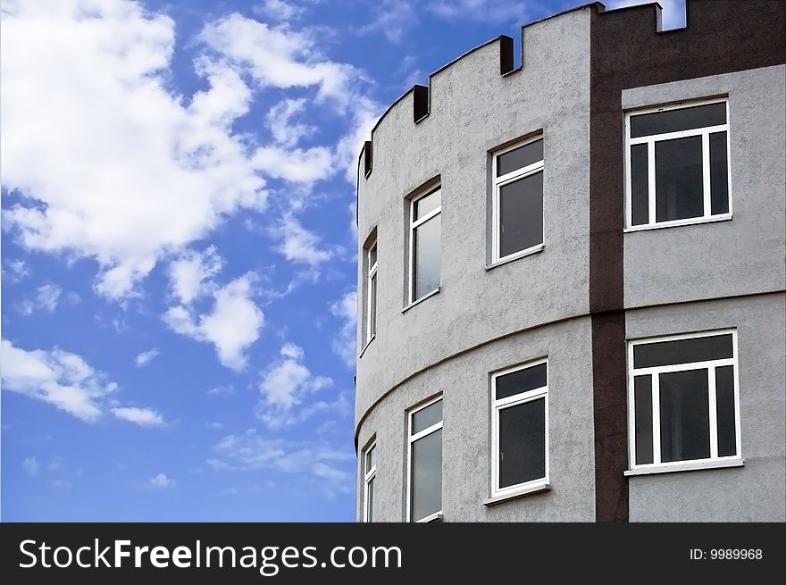 Edge of a tower-like new building with clouds on the background. Edge of a tower-like new building with clouds on the background