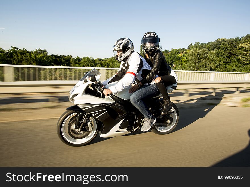 Young men and a women on a motorcycle by day. Young men and a women on a motorcycle by day