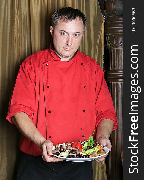 Cook takes off the fried meat and green-stuffs from a sword in a dish