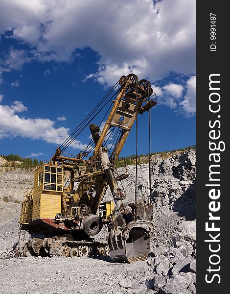 An excavator in opencast mine under skies. An excavator in opencast mine under skies