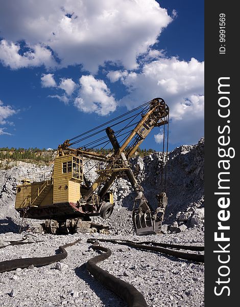 An excavator in opencast mine under skies. An excavator in opencast mine under skies