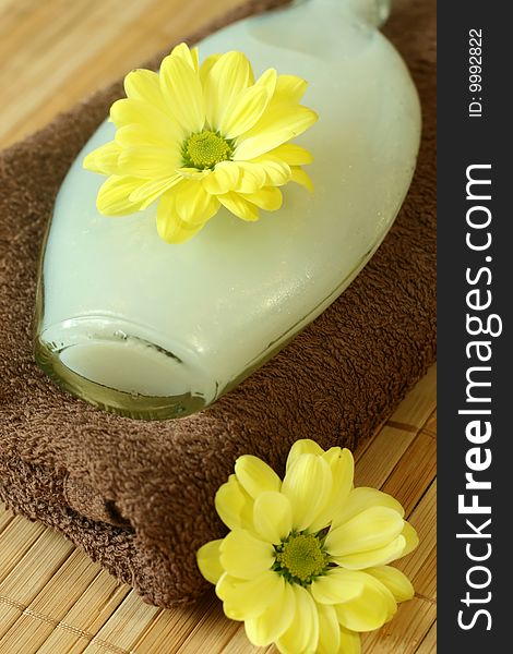 Spa composition of towel, bottle and yellow flowers.