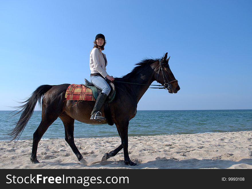 Young girl horseback riding on the beach, smiling at the camera. Young girl horseback riding on the beach, smiling at the camera.