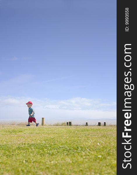 A cute toddler running in the summer sun outside by the sea. A cute toddler running in the summer sun outside by the sea