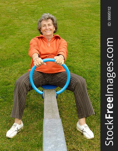 Happy senior woman in orange shirt on a playground. Happy senior woman in orange shirt on a playground