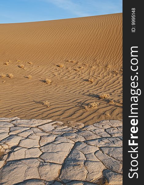 Sand dune with dry cracked earth in front