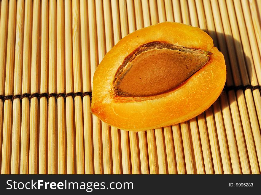 Half of fresh apricot on bamboo mat. Half of fresh apricot on bamboo mat