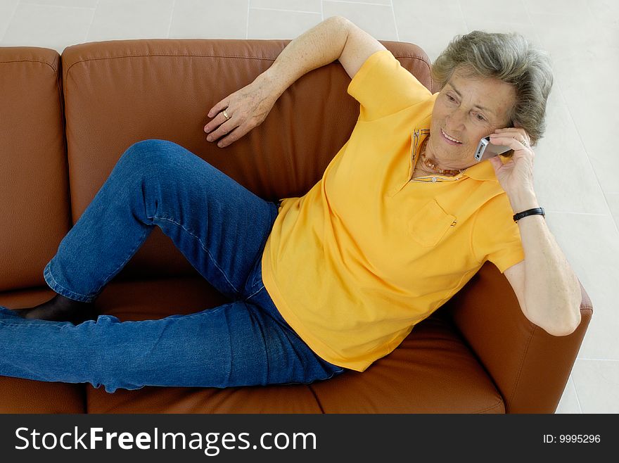 Senior woman with mobile phone on a couch