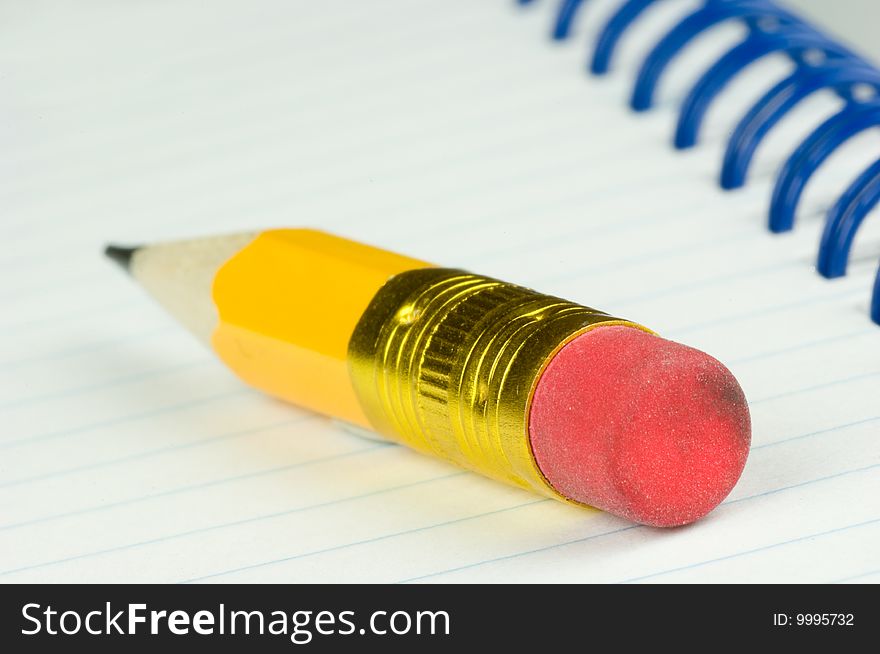 Short yellow pencil with eraser on a notepad. Short yellow pencil with eraser on a notepad