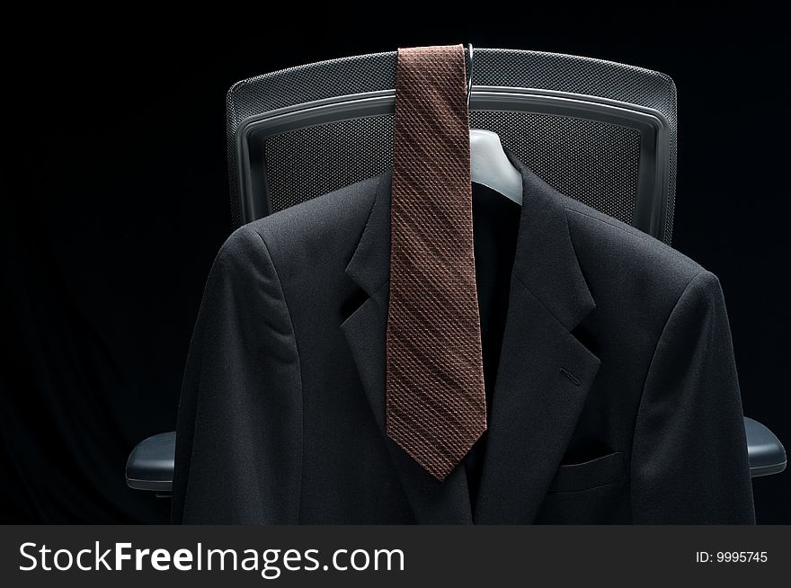 Business jacket and tie hanging on a the back of an office chair. Business jacket and tie hanging on a the back of an office chair