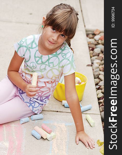 A cute young girl drawing on the sidewalk. A cute young girl drawing on the sidewalk