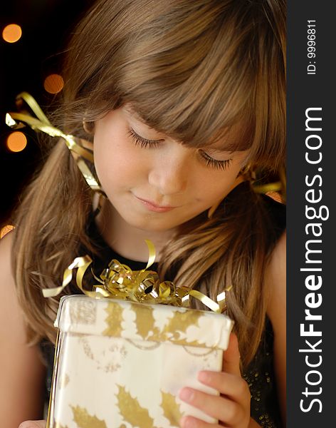 A cute young girl holding a christmas package, christmas light bokeh. A cute young girl holding a christmas package, christmas light bokeh