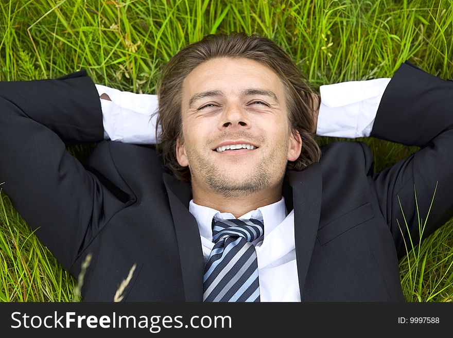 Well-dressed young businessman is resting in a field