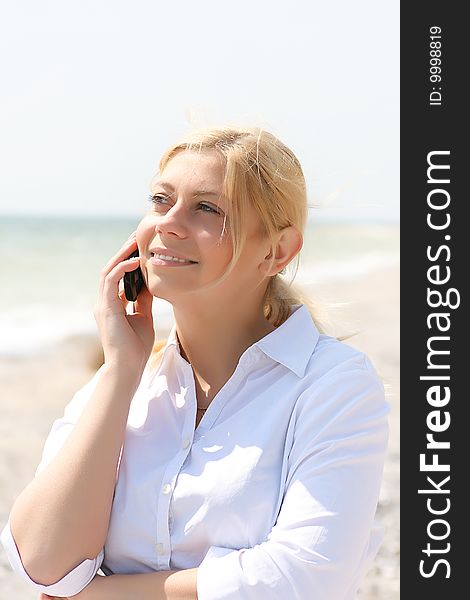 Business woman talks by phone on a beach