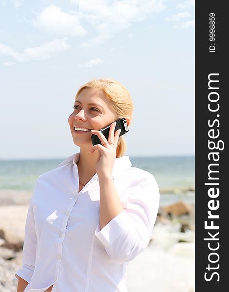 Business woman talks by phone on a beach