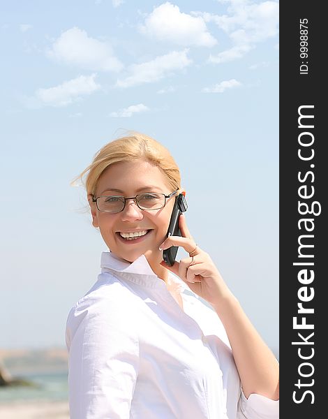 Business woman talks by phone on a beach