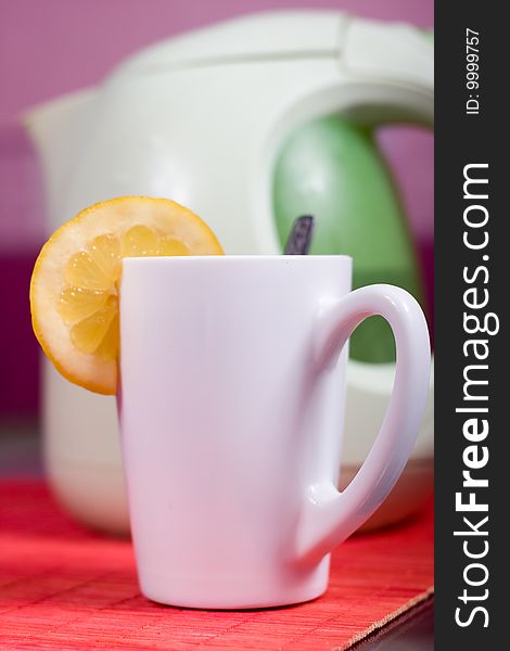 White cup with piece of lemon and kettle. White cup with piece of lemon and kettle