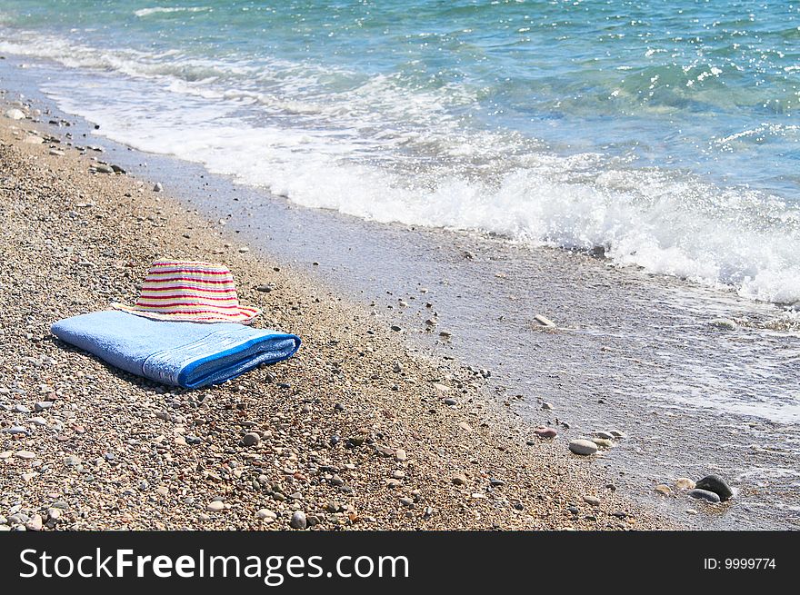 Pink sun hat on the towel next to sea. Pink sun hat on the towel next to sea.