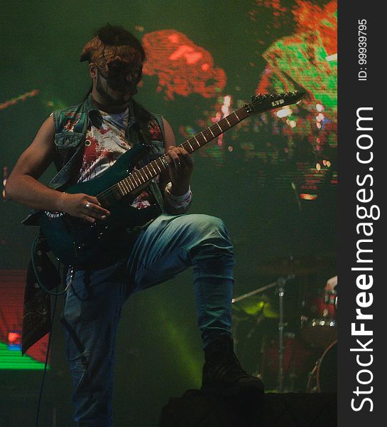 A bass guitar player with a mask on his face. A bass guitar player with a mask on his face.