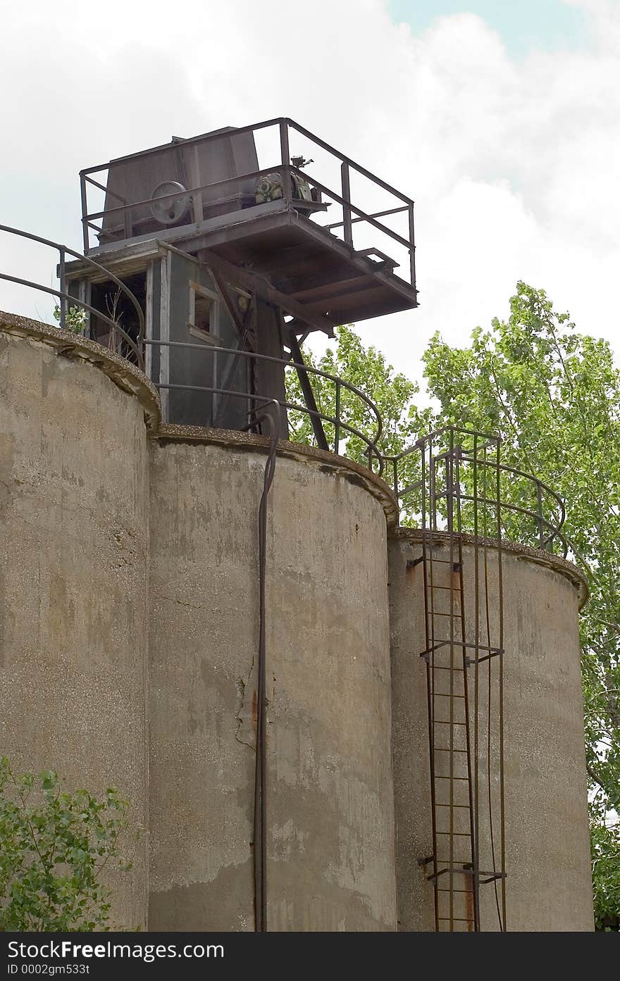 Industrial storage tanks with a platforn on top. A ladder leads to the platform which has a door that allows entry into the tanks. tanks are made of concrete. Industrial storage tanks with a platforn on top. A ladder leads to the platform which has a door that allows entry into the tanks. tanks are made of concrete.