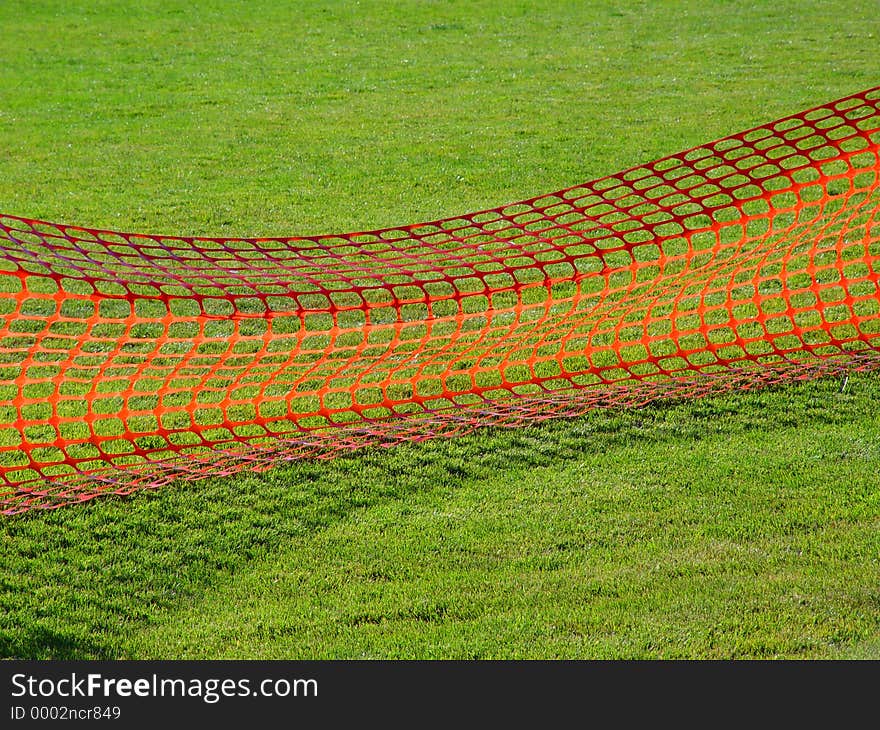 Field of green grass with a red net across