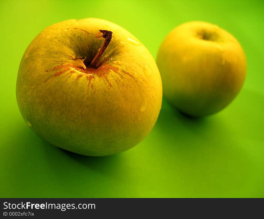 Two grannysmith green apples, focus on the front apple. Two grannysmith green apples, focus on the front apple.