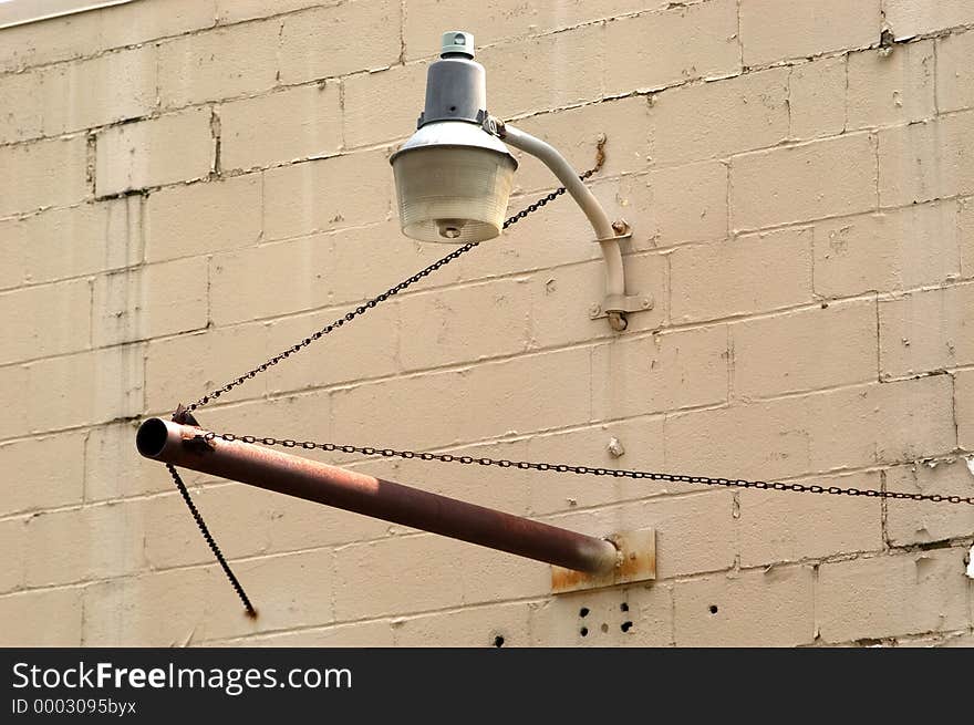 A light hangs over a pipe meant to hold a sign on an abandoned industrial building. A light hangs over a pipe meant to hold a sign on an abandoned industrial building