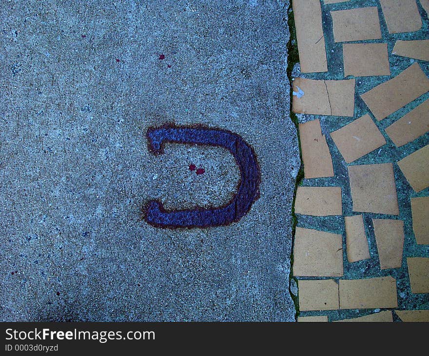 Horsehoe painted on textured sidewalk with stone. Horsehoe painted on textured sidewalk with stone