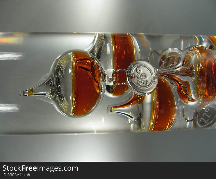 A close-up of an Galileo thermometer. The bubbles are filled with orange liquid. A close-up of an Galileo thermometer. The bubbles are filled with orange liquid.