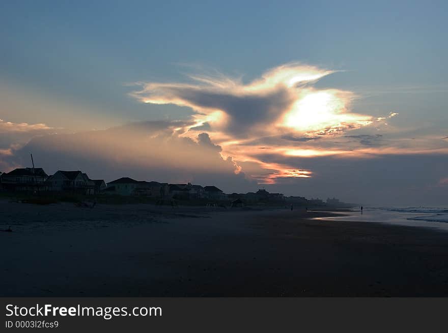 Dramatic sunrise over Emerald Isle, North Carolina. a strong beam of sunlight escapes from the cloud as morning breaks over the waves of the ocean