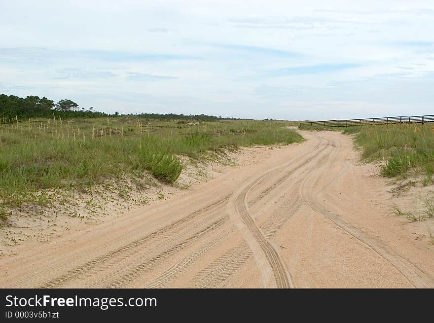 A road leads through the dunes of Cape Lookout, North Carolina. Road is little more than a path of loose sand. A road leads through the dunes of Cape Lookout, North Carolina. Road is little more than a path of loose sand.