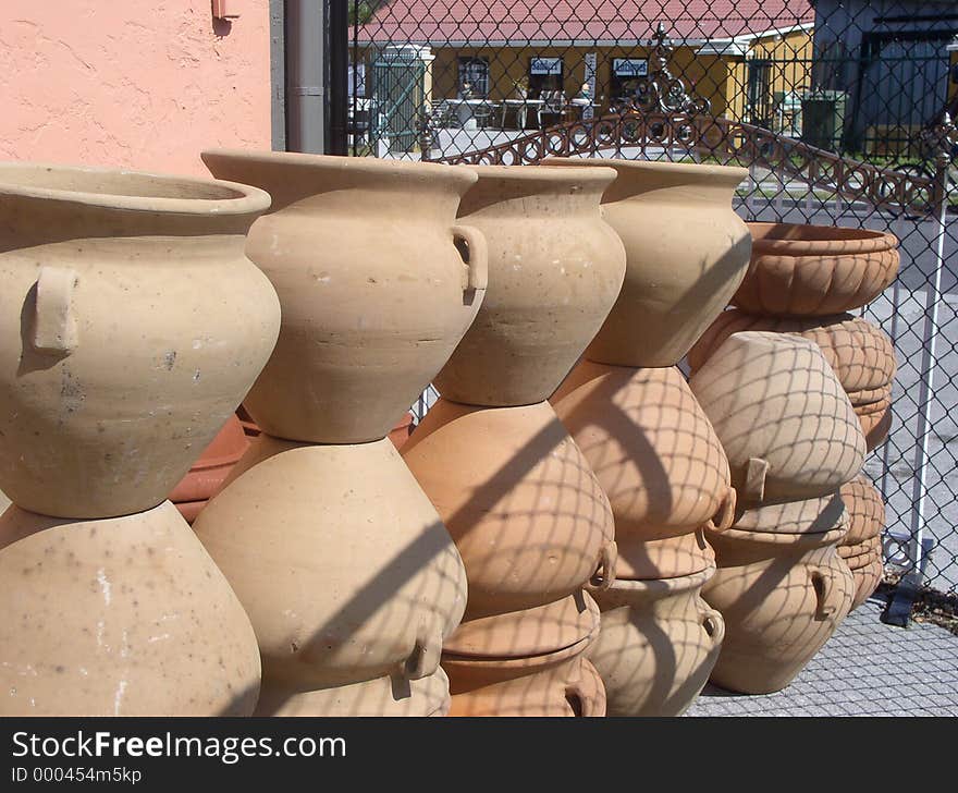 Pile of terra cotta pots with shadow of chain link fence. Pile of terra cotta pots with shadow of chain link fence