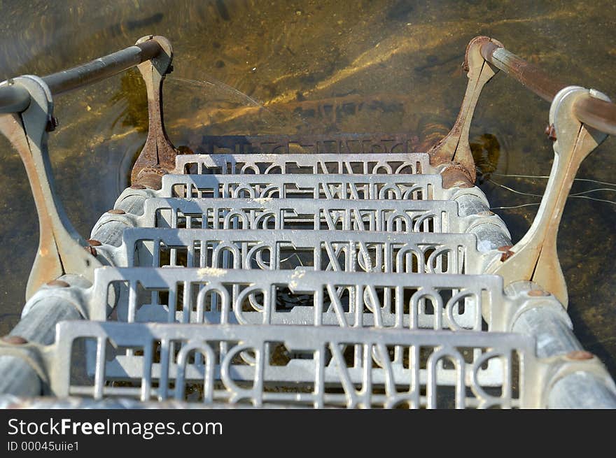 A view looking down a steel ladder, into the water below. A view looking down a steel ladder, into the water below