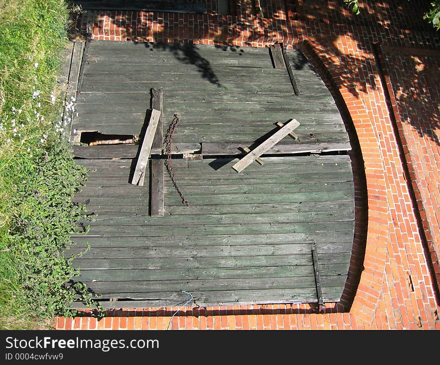 An old broken, weathered barn door in a brick wall.