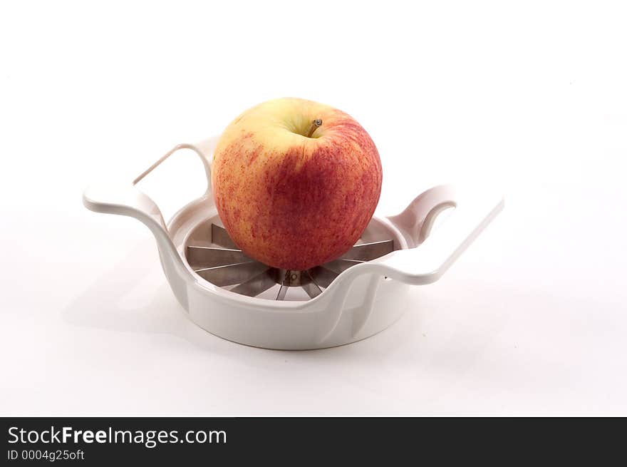 An apple sits atop an apple slicer photographed on a white background. An apple sits atop an apple slicer photographed on a white background