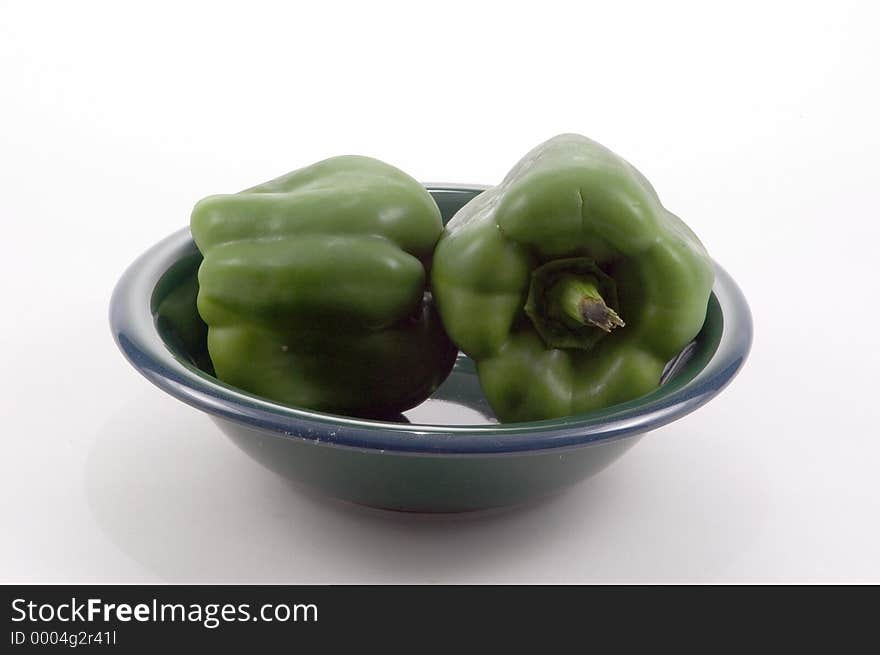 2 large Bell Peppers in a green bowl photographed on a white background. 2 large Bell Peppers in a green bowl photographed on a white background