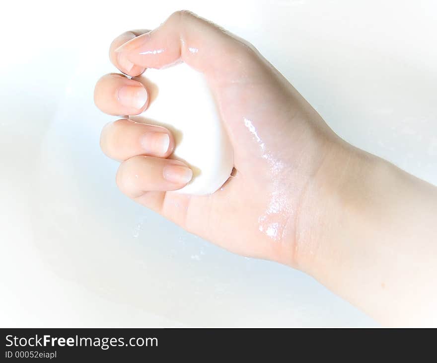 Hand gripping a bar of white soap. High key. Slight shade of pale blue surrounding that hand. Hand gripping a bar of white soap. High key. Slight shade of pale blue surrounding that hand.