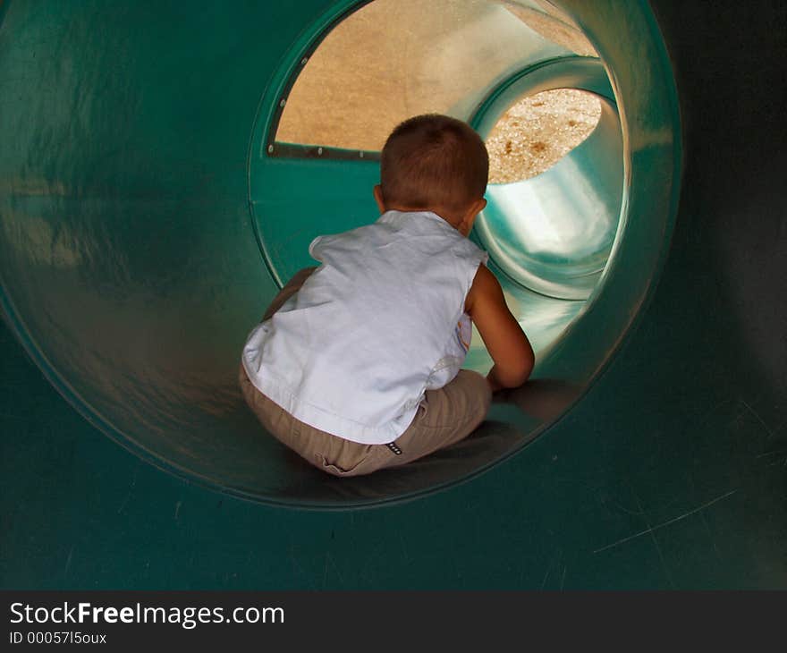 Toddler sliding down a tube slide. Toddler sliding down a tube slide