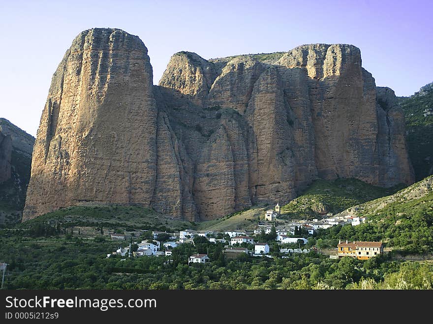 The town of Riglos is dwarfed by the red rock monoliths (mallos) from the Miocene age. The town of Riglos is dwarfed by the red rock monoliths (mallos) from the Miocene age.