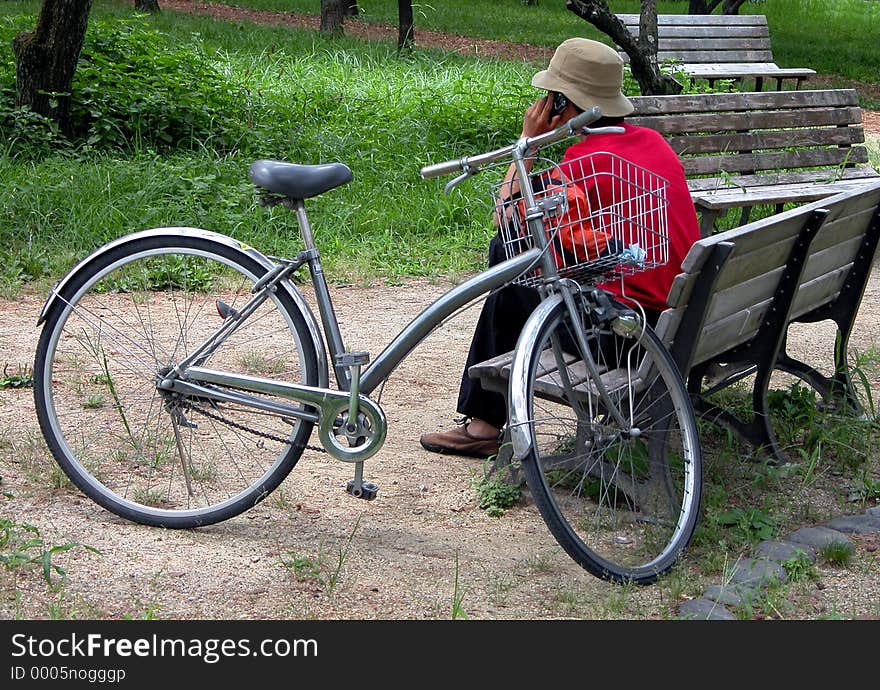 A boy sitting near his bicycle and calling someone. A boy sitting near his bicycle and calling someone