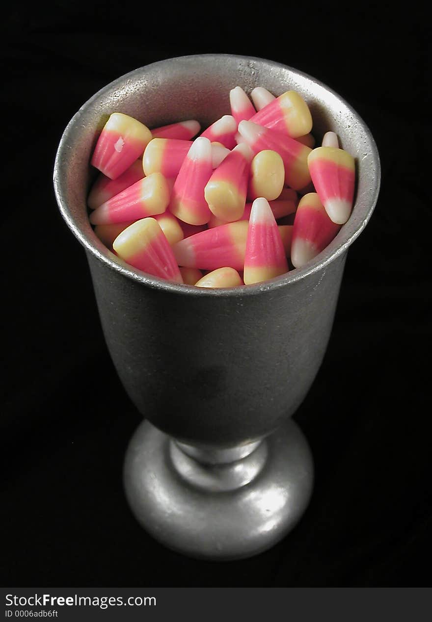 A pewter goblet full of candy corn, on a black background. A gothic look for a favorite halloween treat. A pewter goblet full of candy corn, on a black background. A gothic look for a favorite halloween treat.