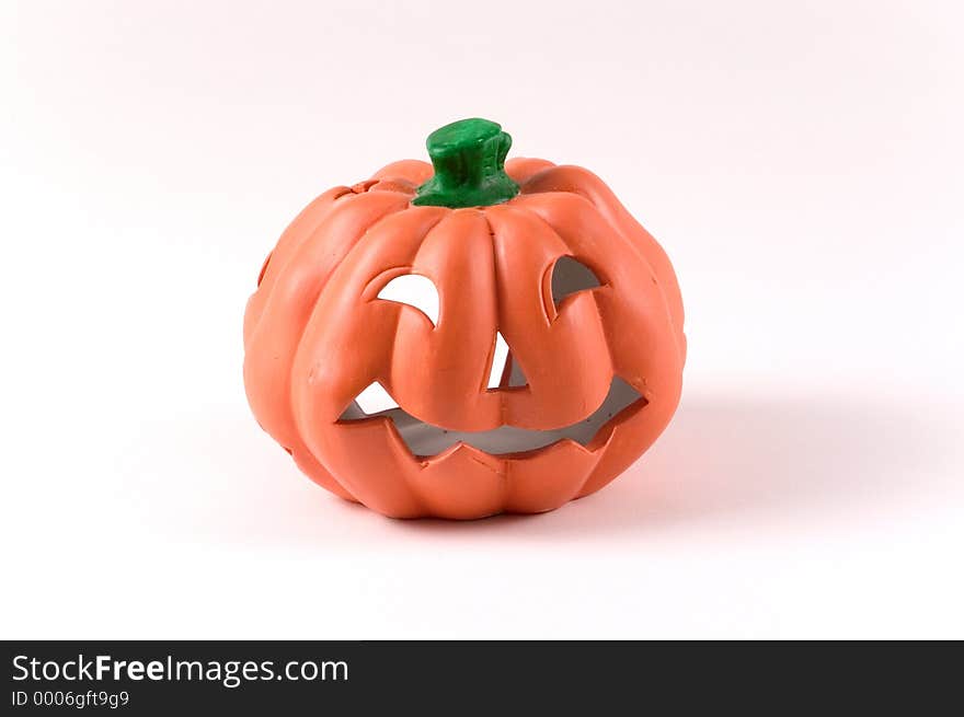 A small ceramic pumpkin decoration for Halloween. Pumpkin has jack-o-lantern face carved on it.