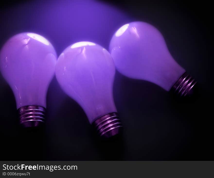 3 white, matte light bulbs in a dark environment. Purple tones, soft focus. 3 white, matte light bulbs in a dark environment. Purple tones, soft focus.