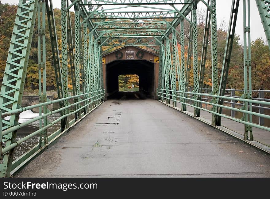 Looking across the roadway of a covered bridge in Northeastern Ohio. A more modern metal span leads to the older covered bridge.