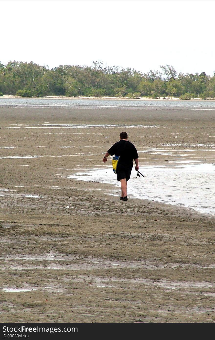 A lone fisherman going out at low tide. A lone fisherman going out at low tide