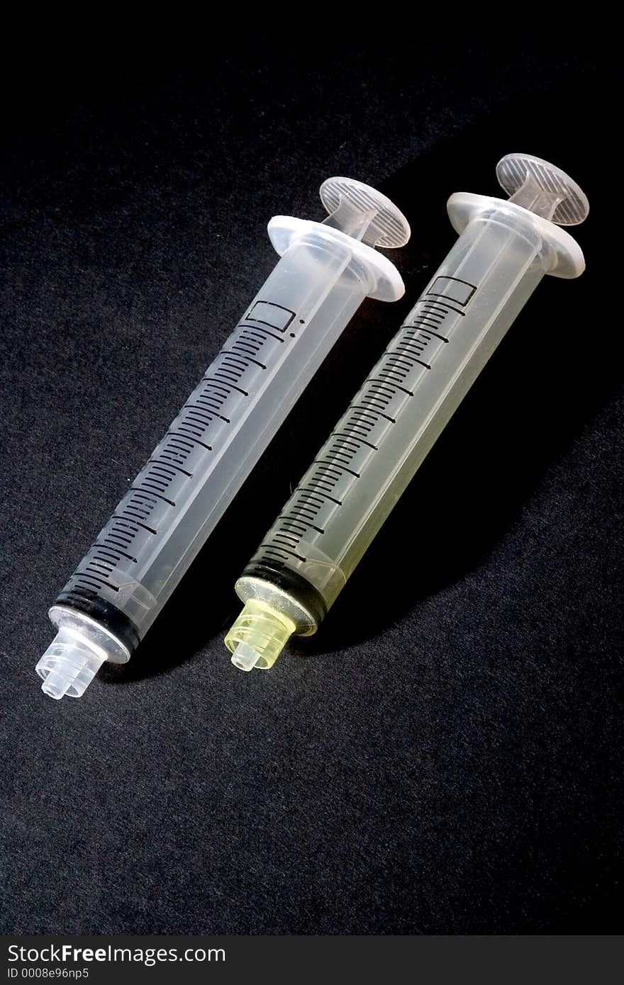 A pair of syringes photographed on a black background. A pair of syringes photographed on a black background