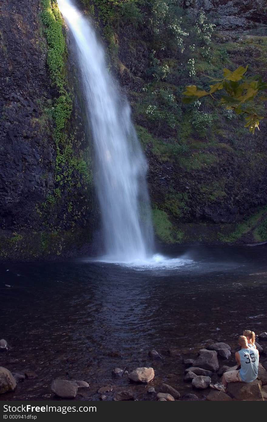 Couple sitting in front of waterfall.